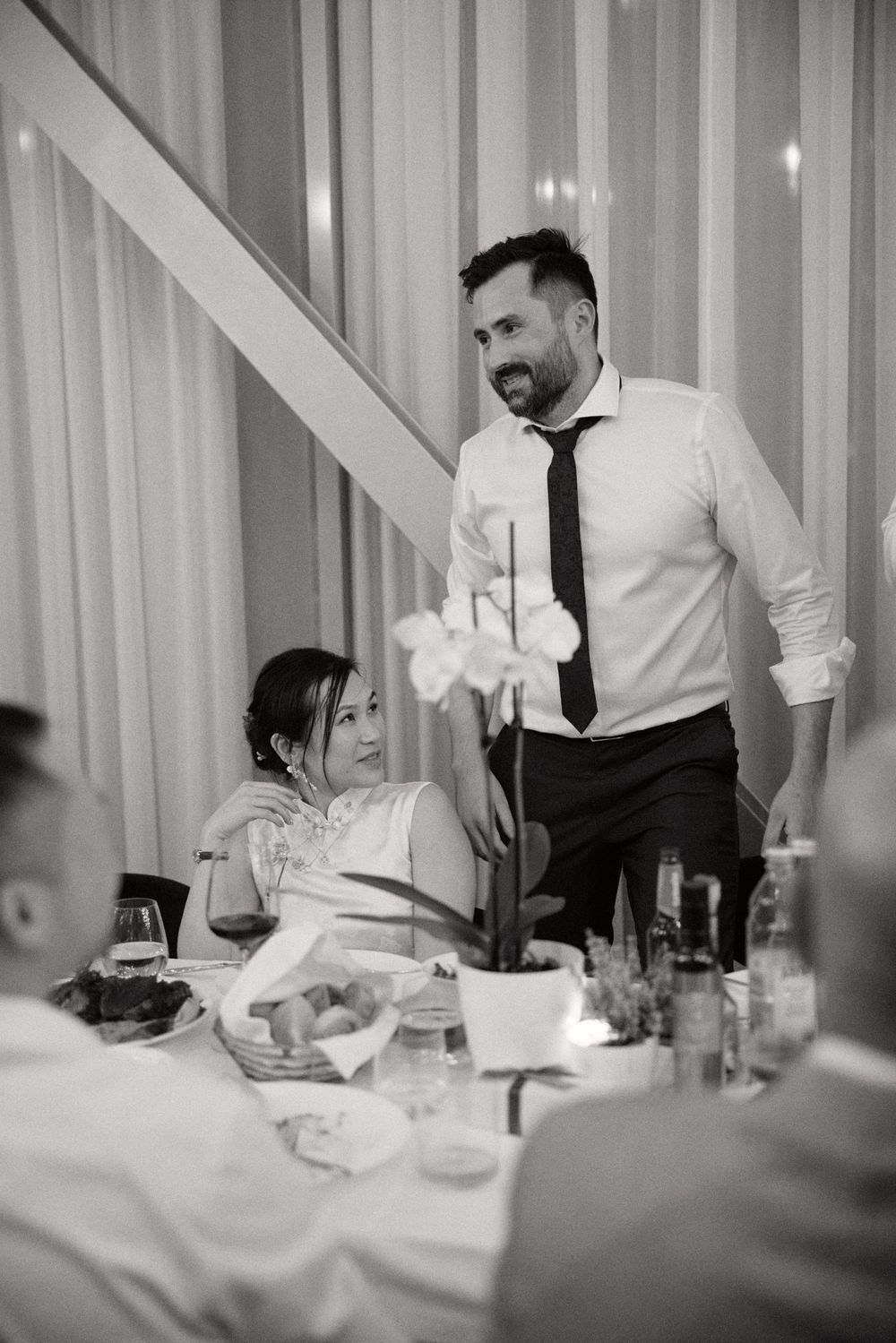 Wedding reception service staff in white shirts and black ties attending to dining tables.