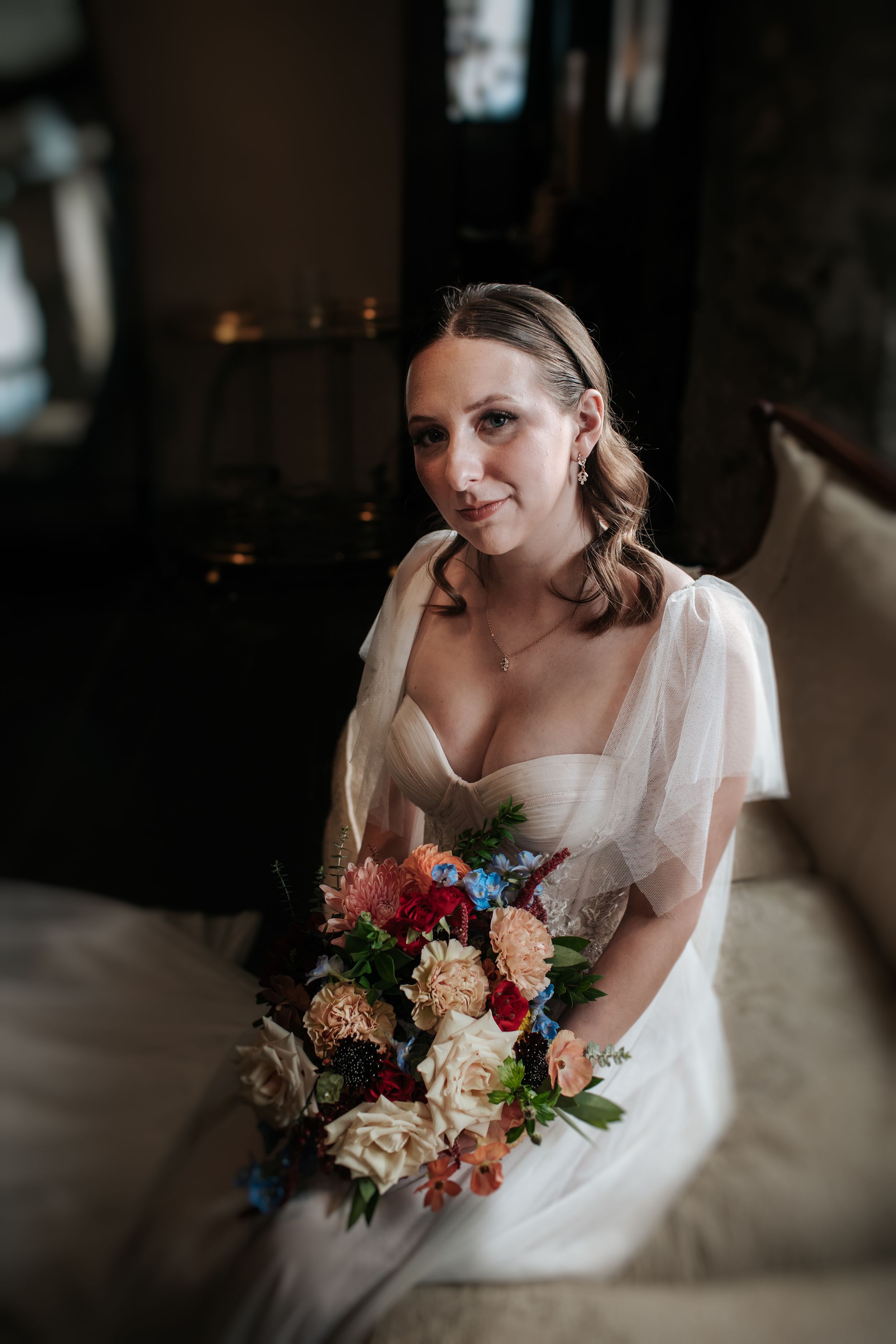 A bride in a white dress holds a vibrant bouquet featuring pink, blue and peach flowers in a series of artistic portraits.