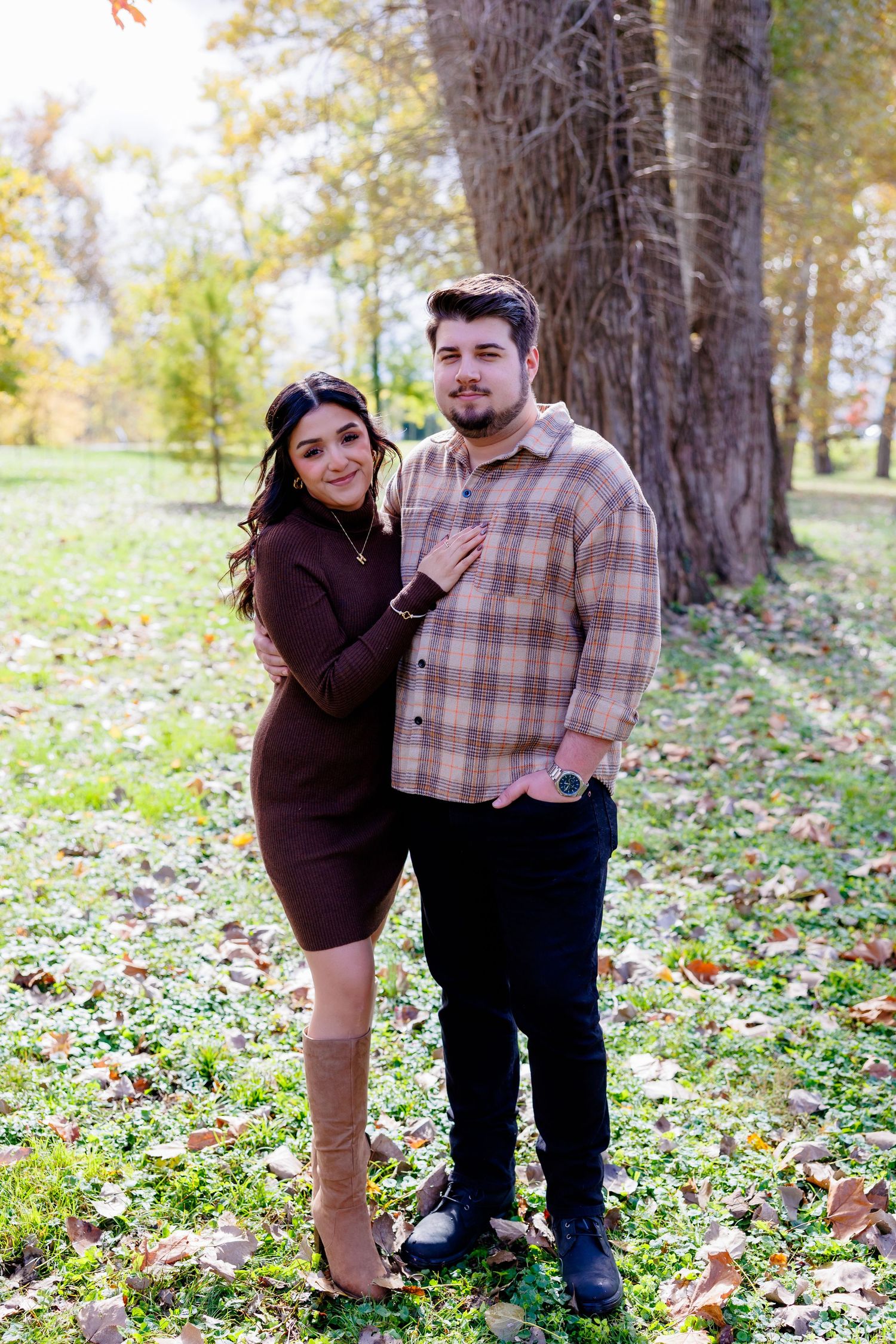 A couple enjoys a romantic autumn day outdoors surrounded by colorful fall foliage near a lake.