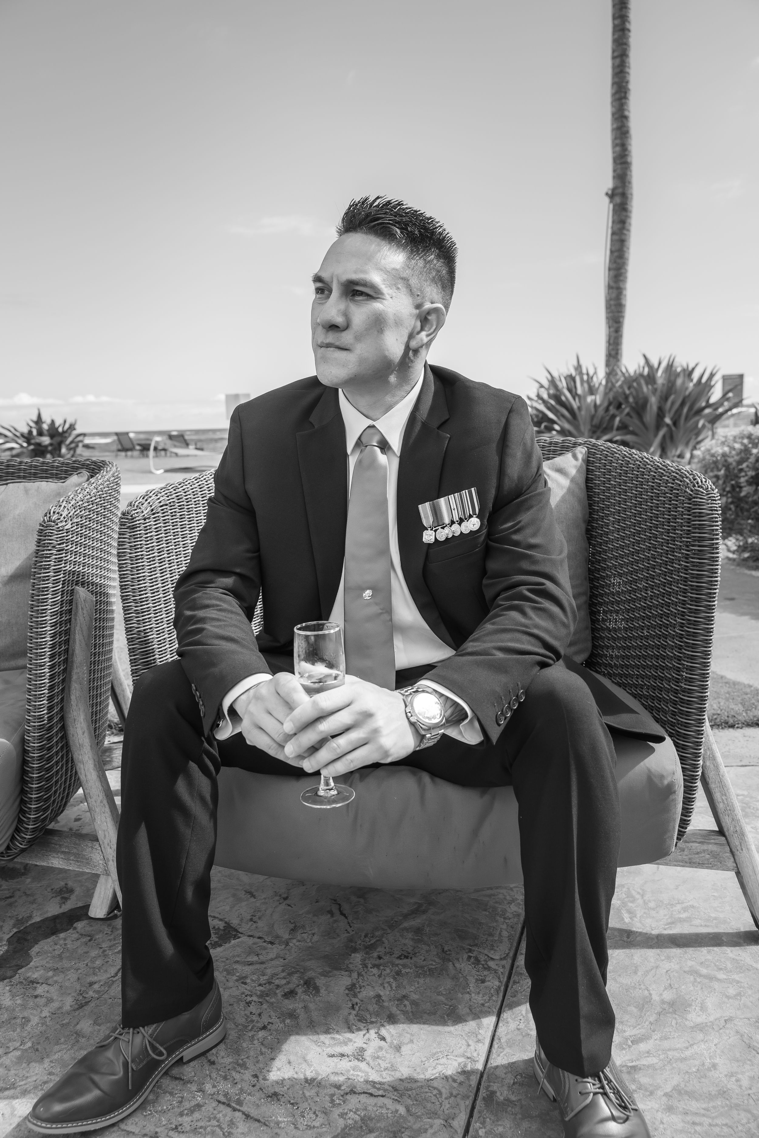 Black and white photo series showing a person in a suit sitting on outdoor furniture at different angles.