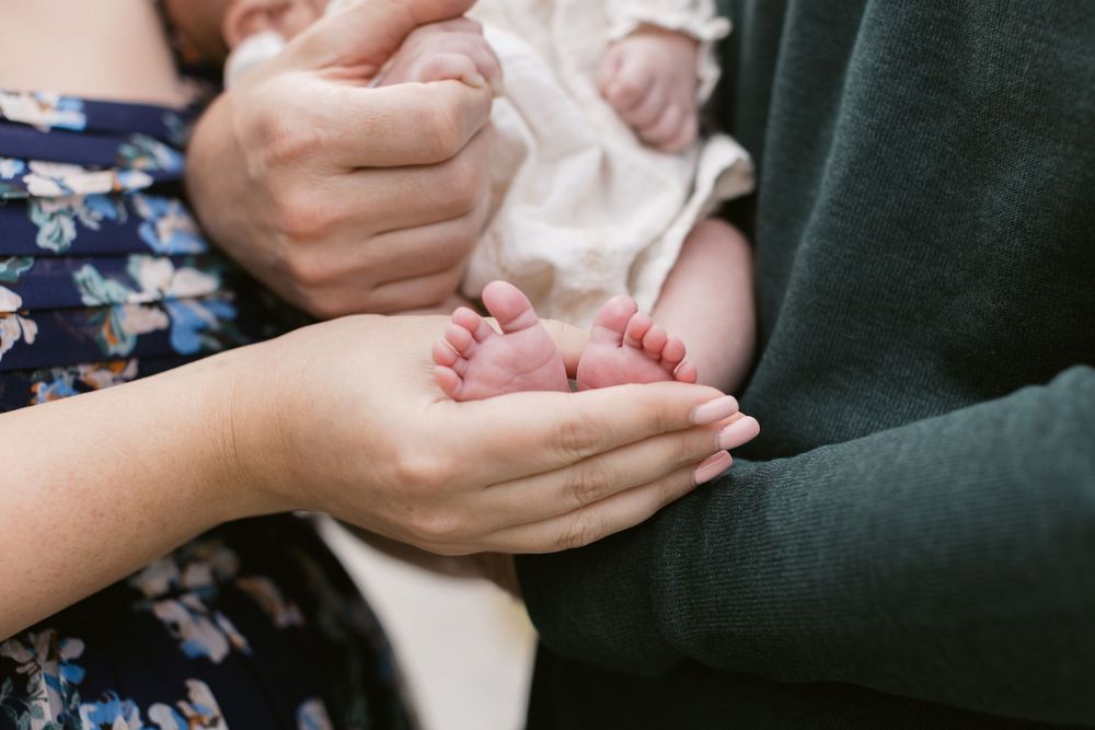 A couple embraces their newborn's feet at Whiteface Hallow in Tamworth Lakes Region White Mountains New Hampshire for a newborn shoot