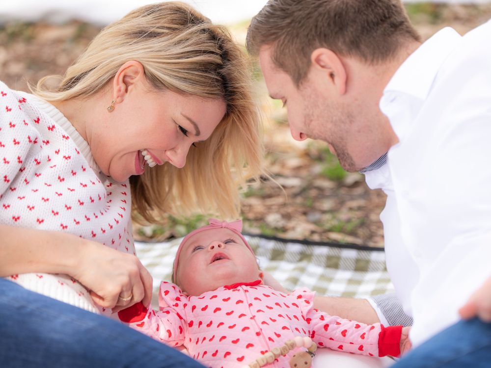 A happy family enjoys a tender moment together while laying on a blanket outdoors.