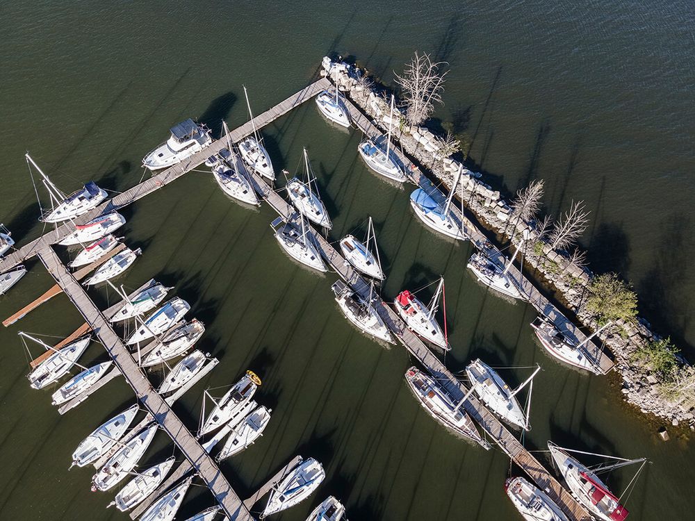 Marina filled with sailboats and yachts docked in neat rows on calm waters.
