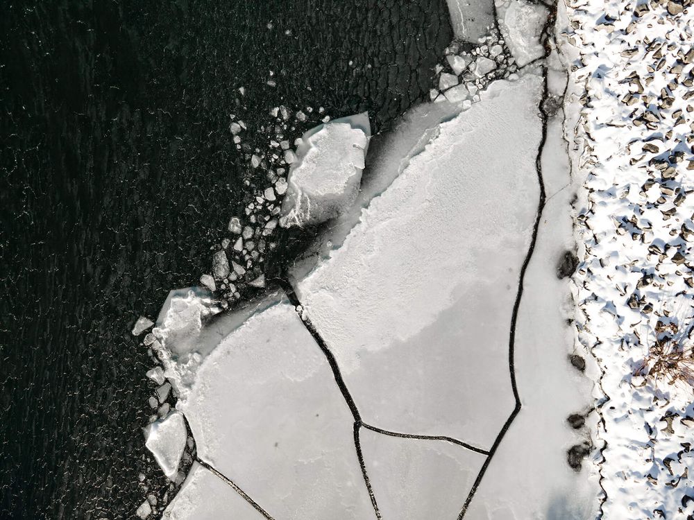 Frozen lake surface with geometric crack patterns in white snow cover.