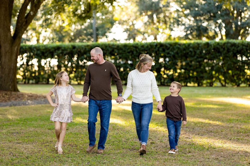Family members walking together on a sunlit grassy path through a park during golden hour.