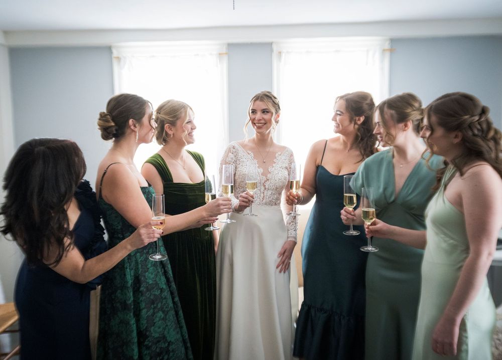 A panoramic view of bridesmaids in black and green dresses getting ready before a wedding ceremony.
