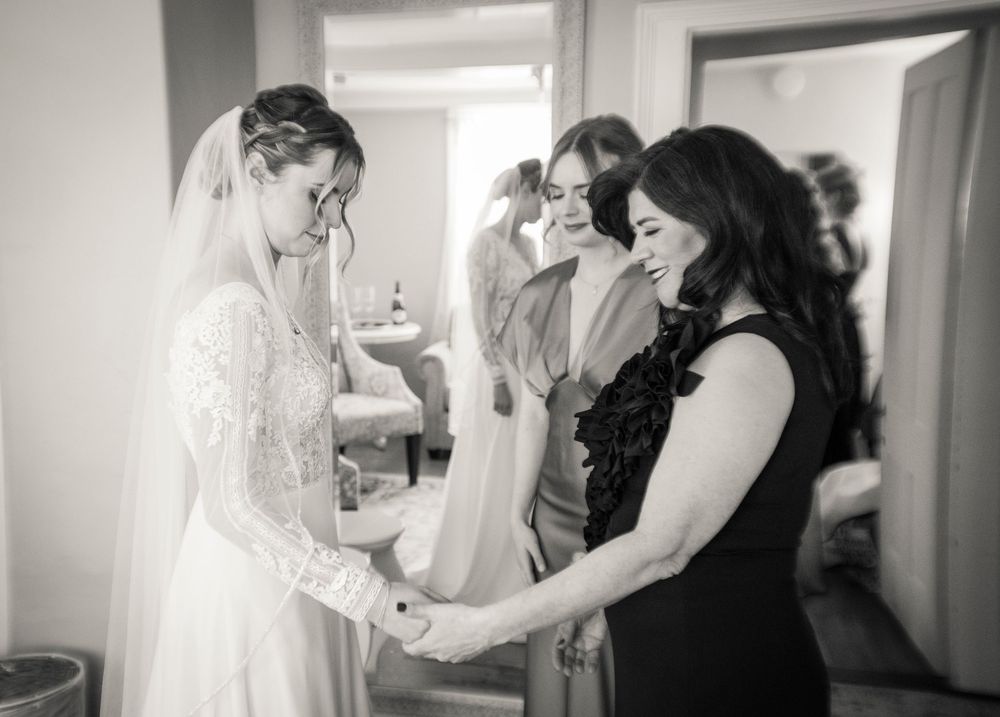 Black and white photo showing wedding preparations with attendants helping with final details.