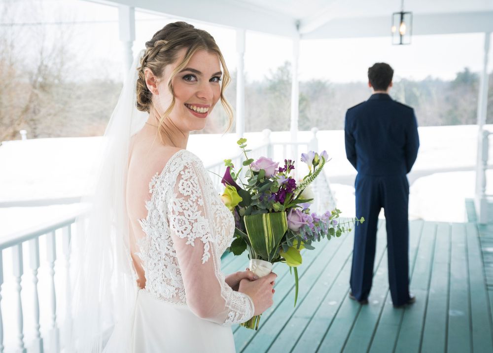 Wedding party members and formal attire on a bright sunlit porch with winter scenery visible through windows.