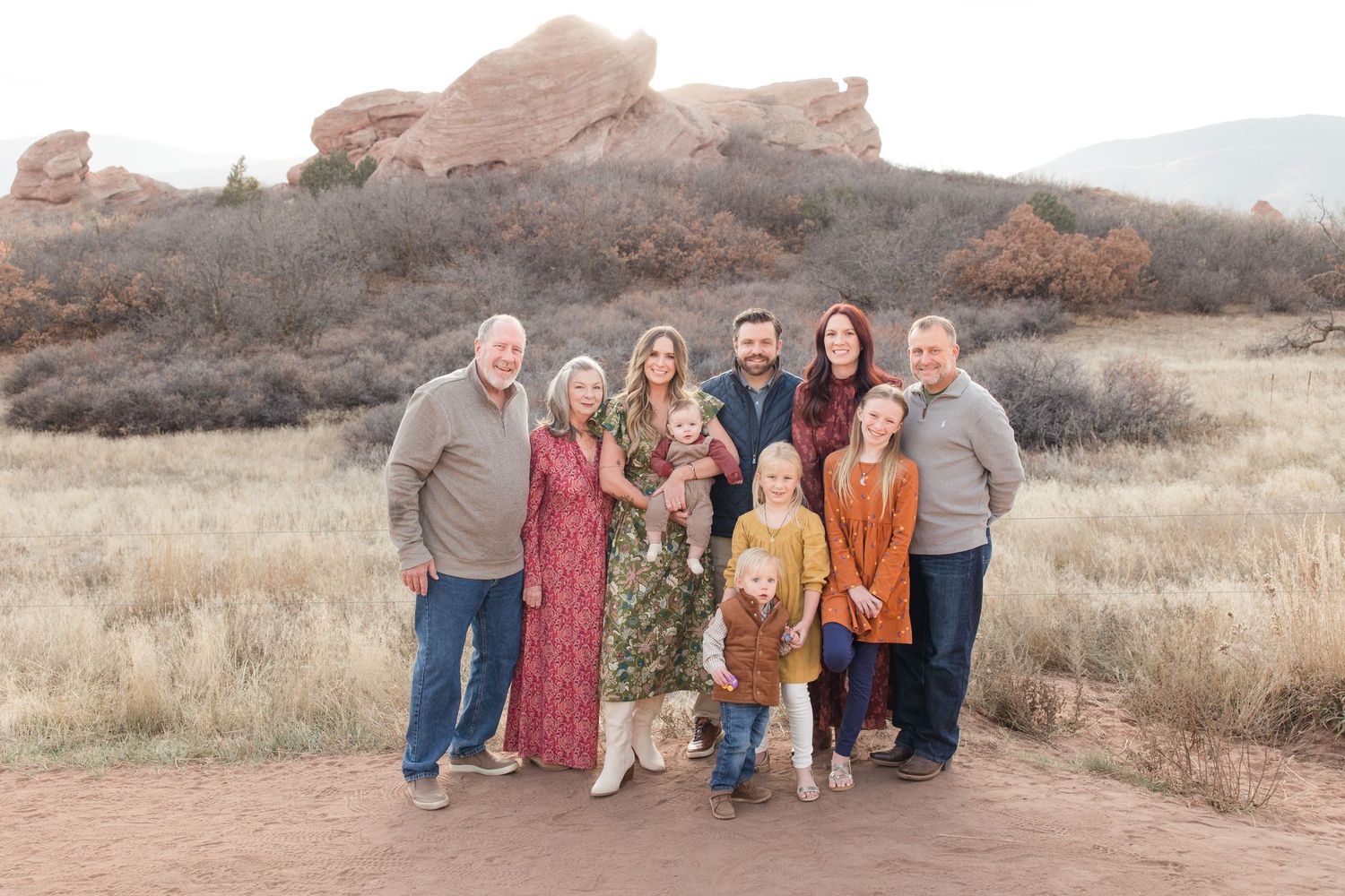 Family group poses together on hiking trail with desert mountains in background.
