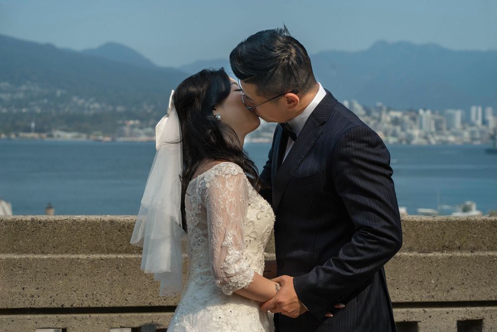 Couple exchanging vows during outdoor wedding ceremony with scenic coastal backdrop.