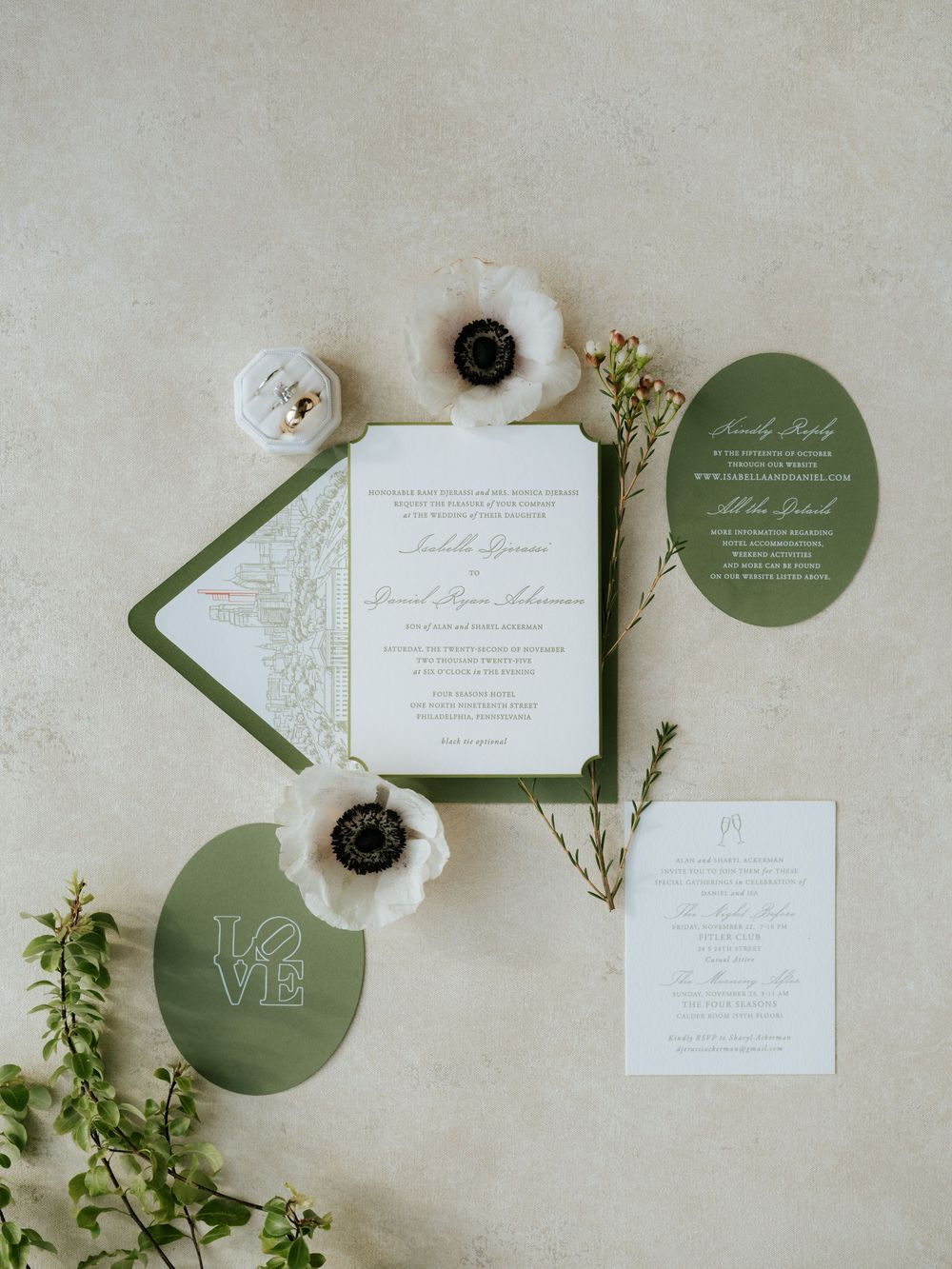 Elegant wedding invitation suite in sage green and white with anemone flowers and greenery styled on light background.