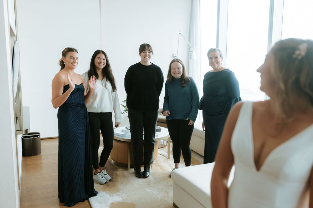 Bright white studio space with large windows and people gathered for a wedding preparation event.
