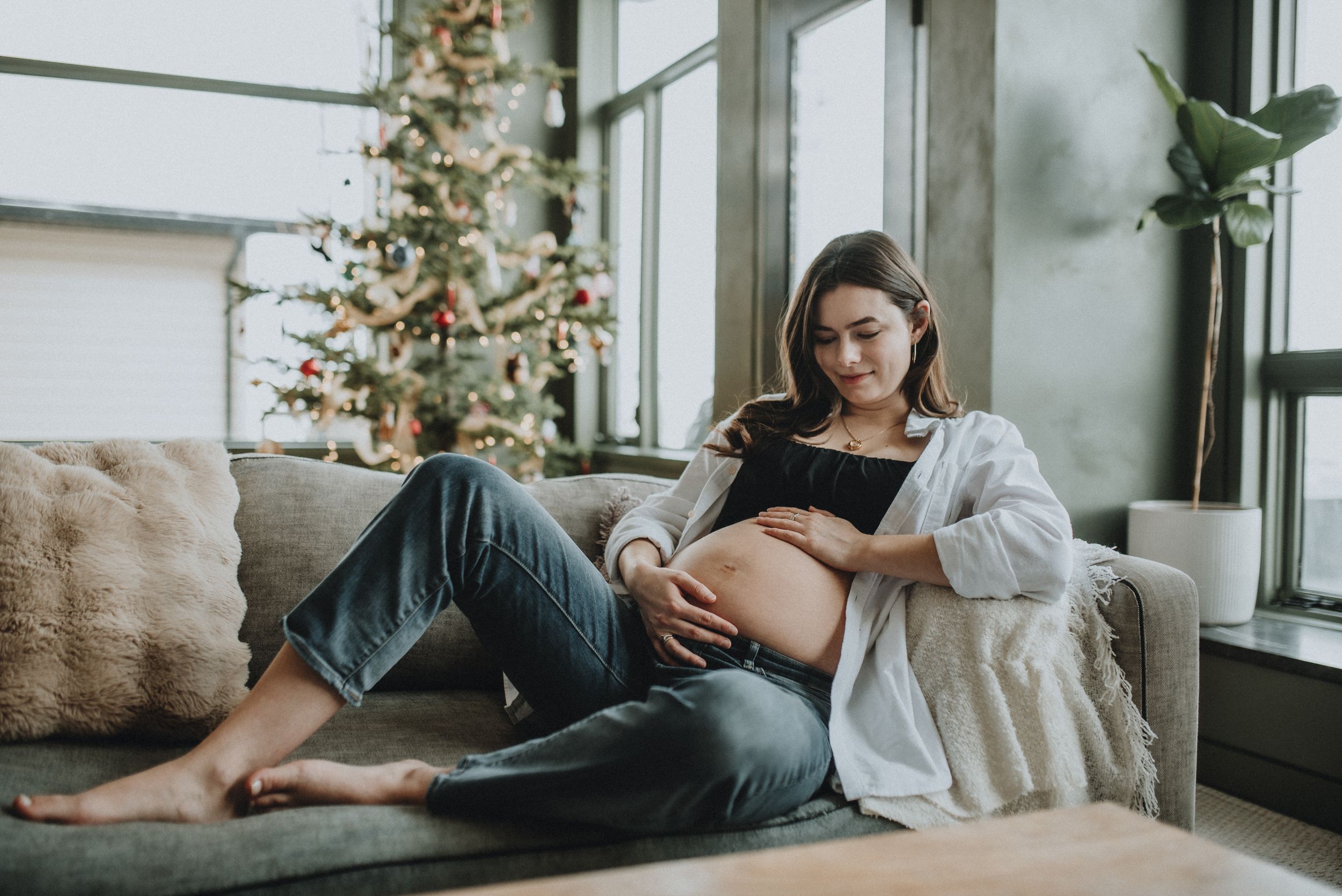 a pregnant mom gazes upon her growing pregnant belly in anticipation of her baby soon to be born in Cochrane alberta