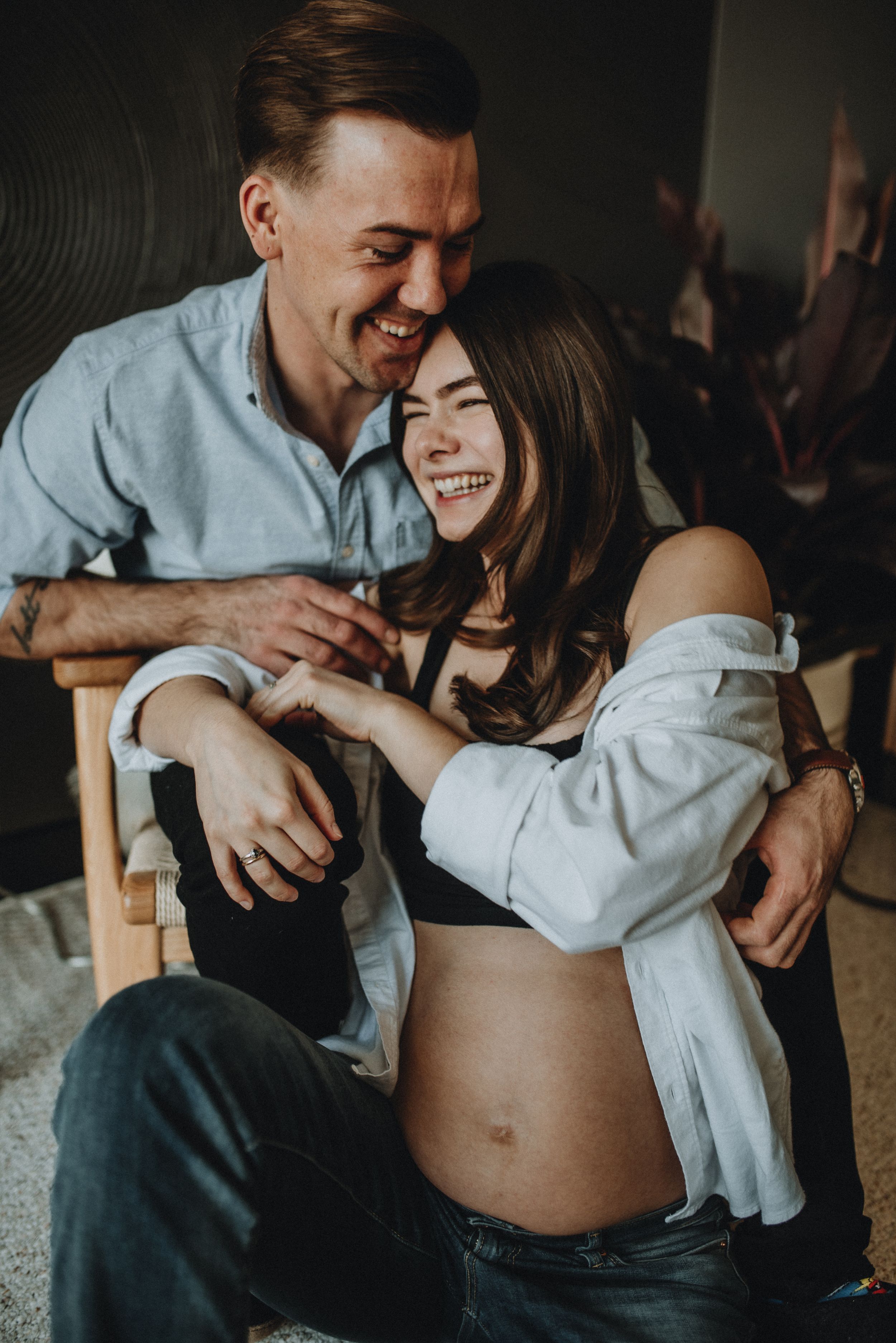 a couple embrace and laugh together during this maternity shoot in Cochrane Alberta