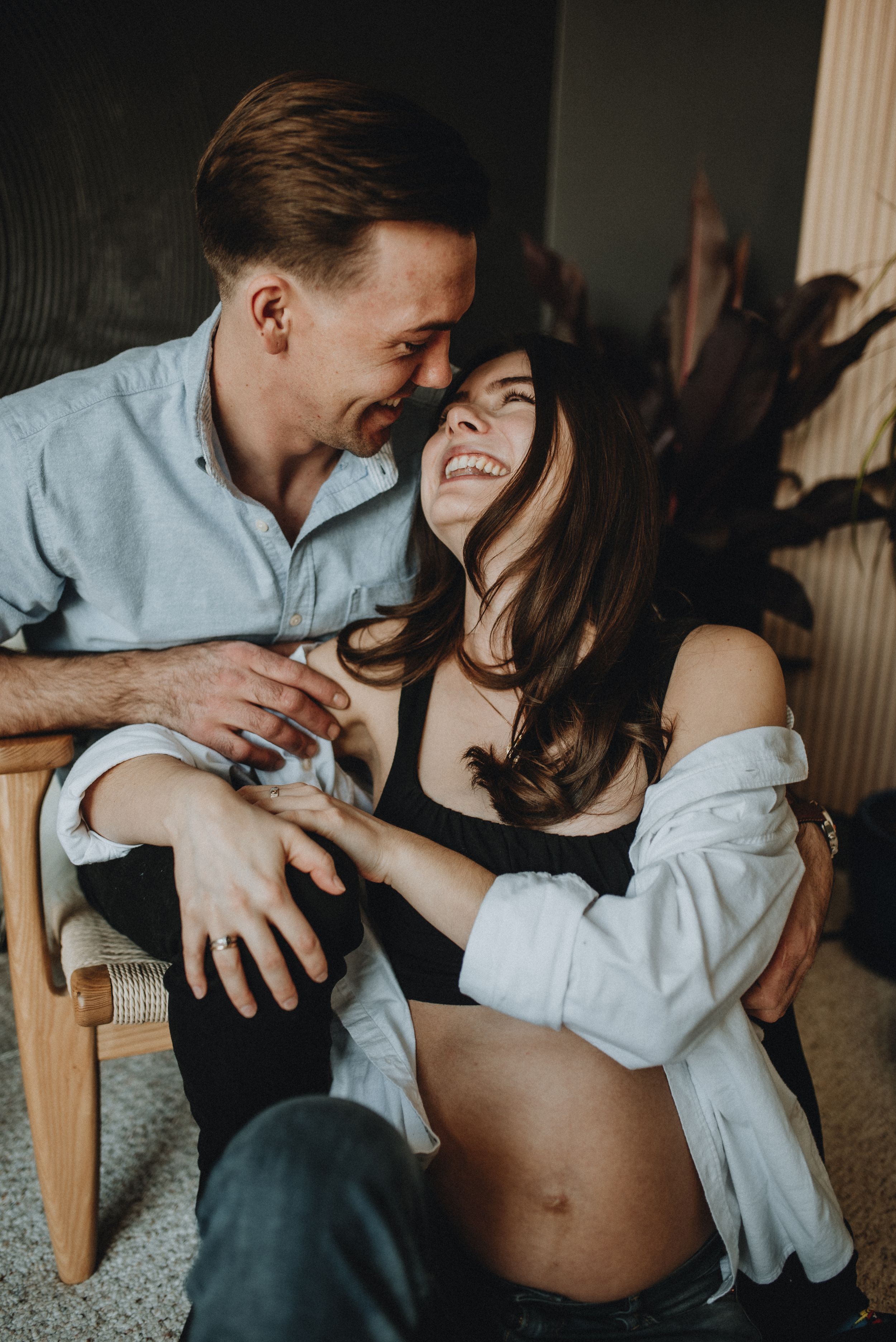 a couple embrace and laugh together during this maternity shoot in Cochrane Alberta