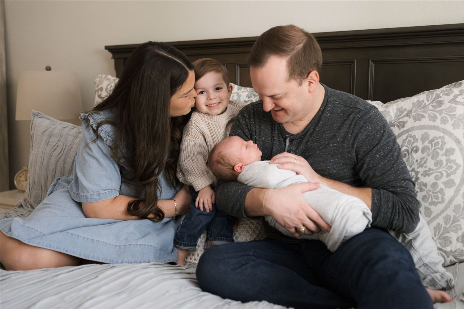 A family relaxes together on a cozy bed of their home in The Woodlands Texas