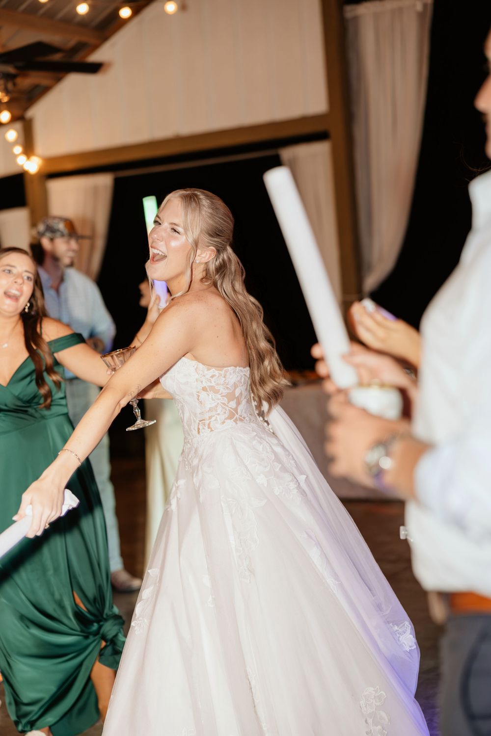 Wedding party guests dancing and celebrating on the dance floor at a reception with string lights overhead in Coosada, Alabama