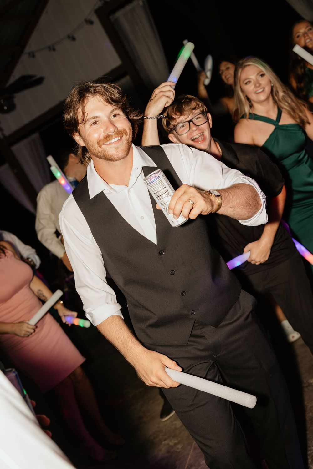 Wedding guests dance with glowing light sticks at a reception party as they celebrate on the dance floor at The Elms of Coosada in Coosada
