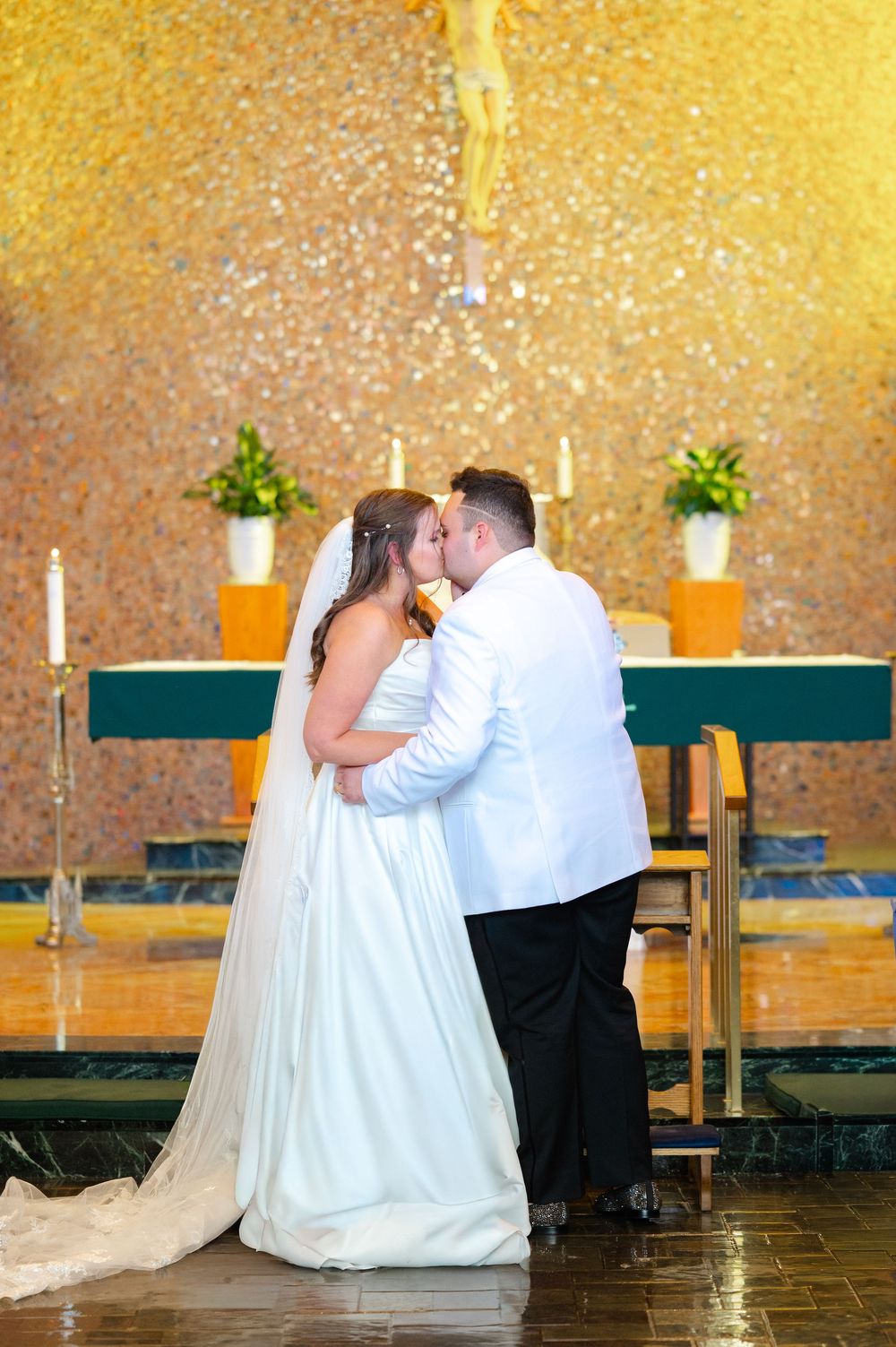 Romantic wedding couple sharing intimate moments in an elegantly lit venue with golden backdrop and candles.
