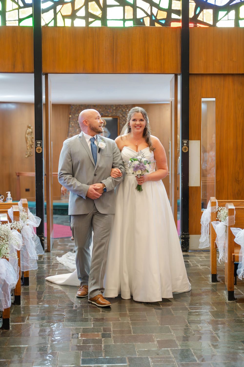 A wedding couple walks down a modern hallway with stone floors and wooden walls in a sequence of progressive shots.