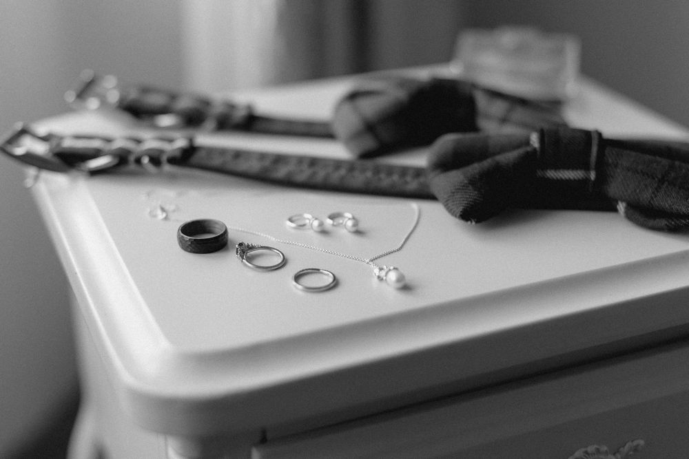 Black and white photo showing a vintage gaming controller with buttons and joystick on a wooden surface.