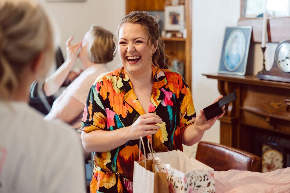 A person in a colorful butterfly print dress laughs joyfully while seated at a dining table.