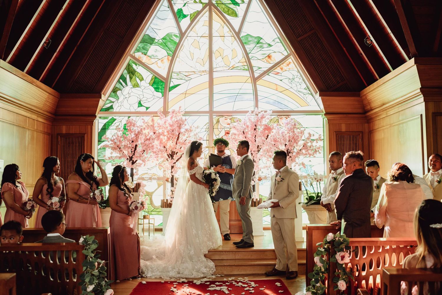 Wedding ceremony in a chapel with stained glass windows and wooden beam architecture.