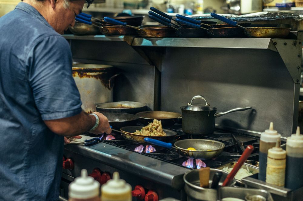 Chefs preparing food on a commercial grill with steam rising.
