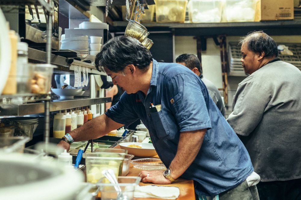 Chefs working in a busy commercial kitchen line.