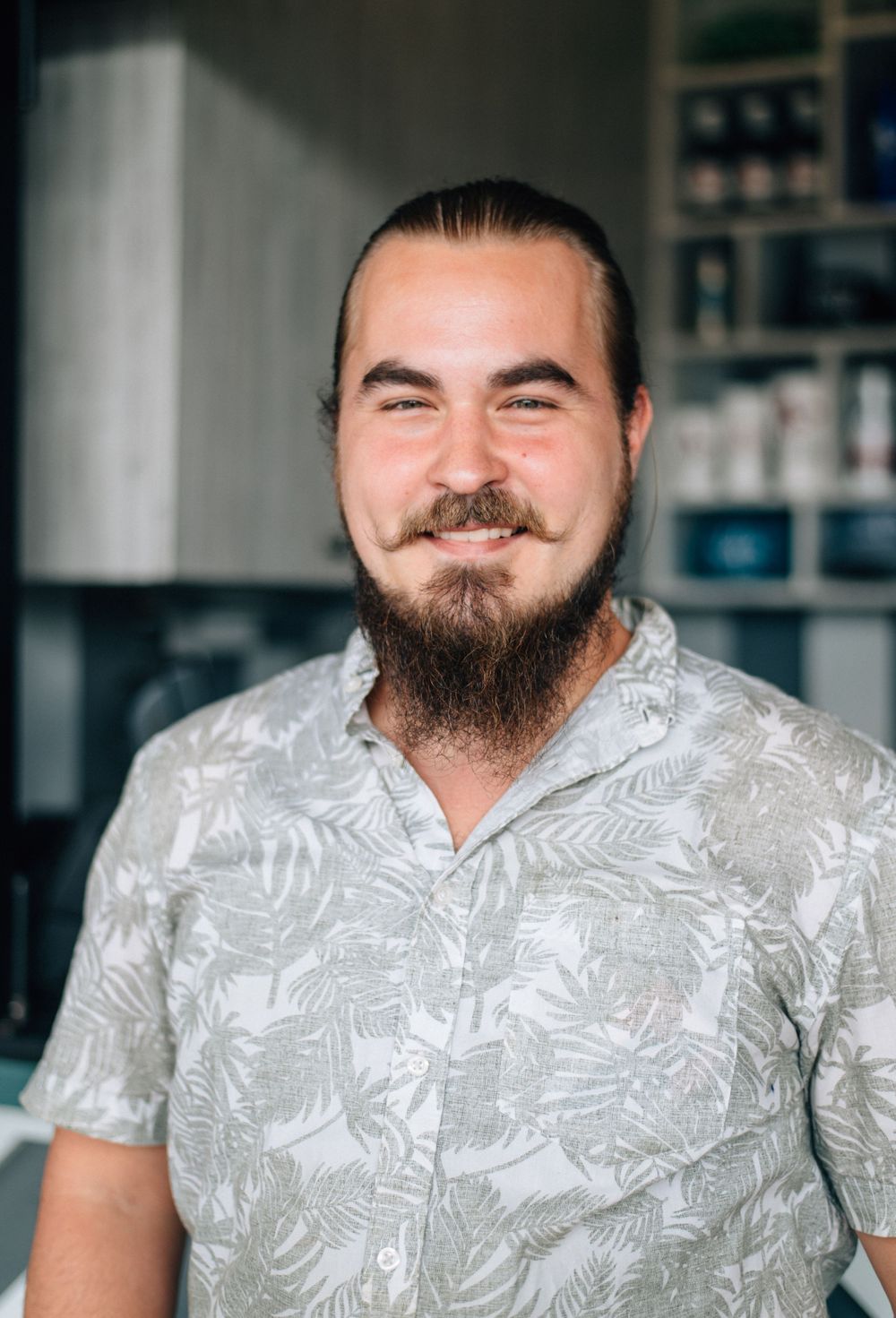 Person wearing a light gray floral print shirt in an indoor setting.