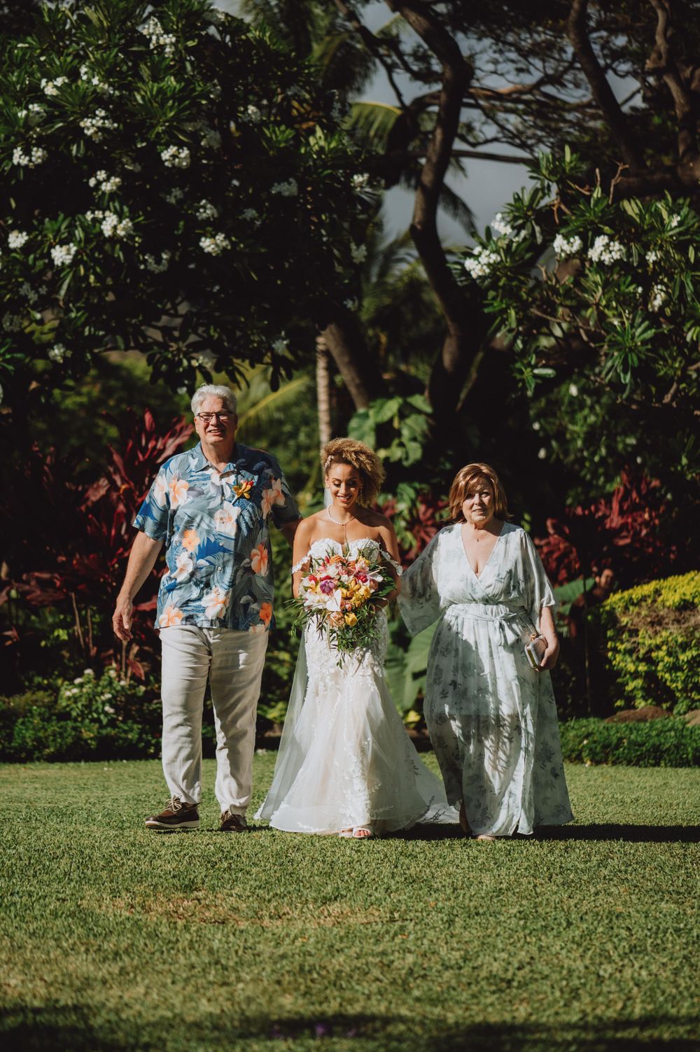 Wedding guests walk across a lush green lawn during an outdoor ceremony.