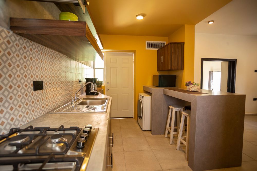 Wide angle view of apartment interior with yellow walls and tiled flooring.
