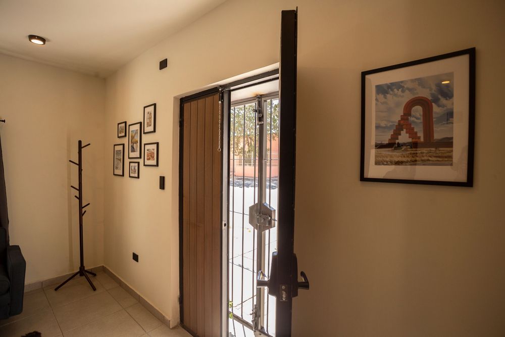 Long hallway with framed artwork on beige walls and natural lighting from windows.