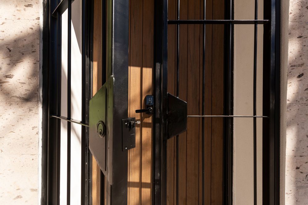 Row of black metal security bars on windows casting shadows against a light colored wall.