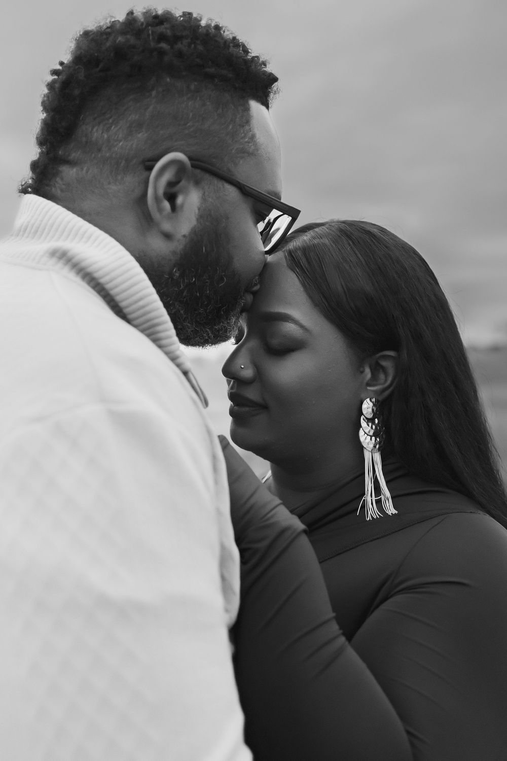 Intimate black and white portrait of a couple in an embrace, with the woman wearing dangling earrings.