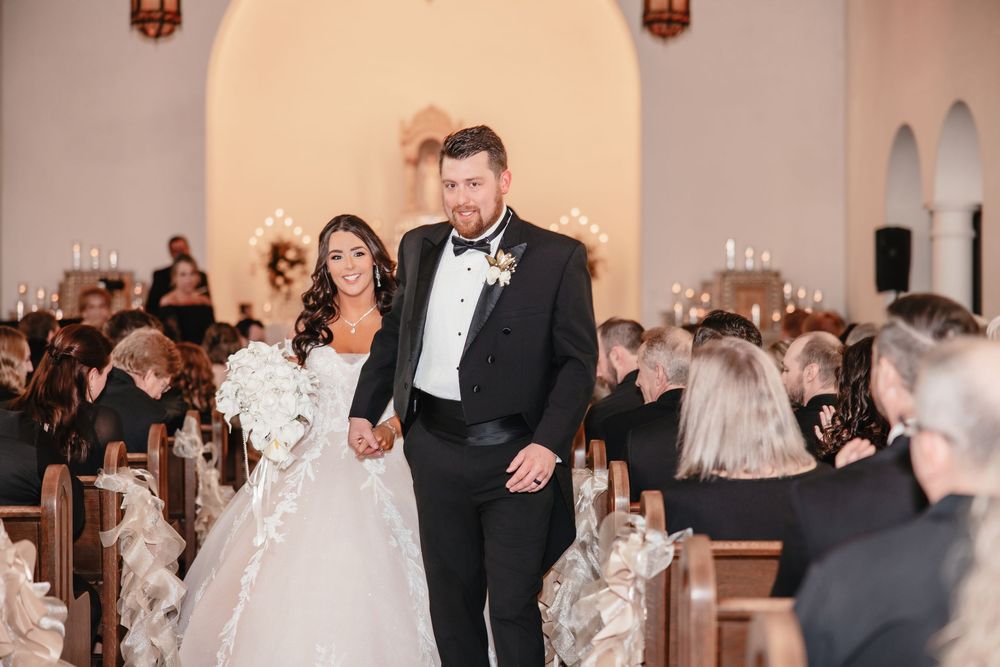 Guests mingling at formal event in white interior space with warm lighting.