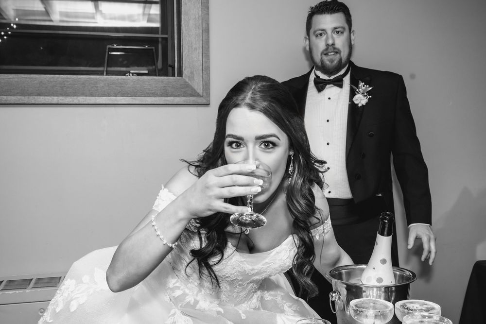 Bride and groom clink glasses in an elegant indoor setting during their wedding celebration.