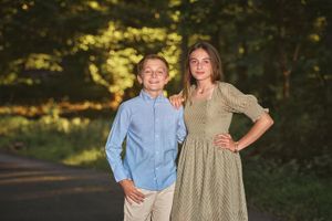 Tween brother and teen sister embracing on their wooded driveway outside the Baltimore area.