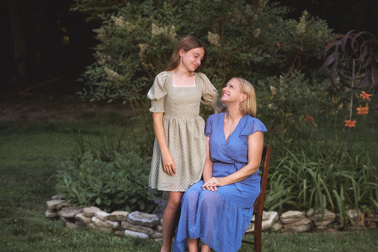 Seated mom and teen daughter gazing at each other in their Baltimore outskirts  garden.