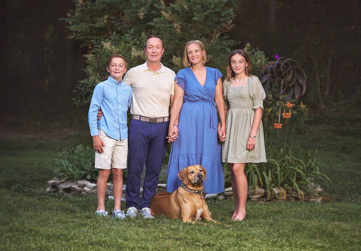 Mother, father, teen son and daughter and family dog standing in front of back yard garden in Joppa MD