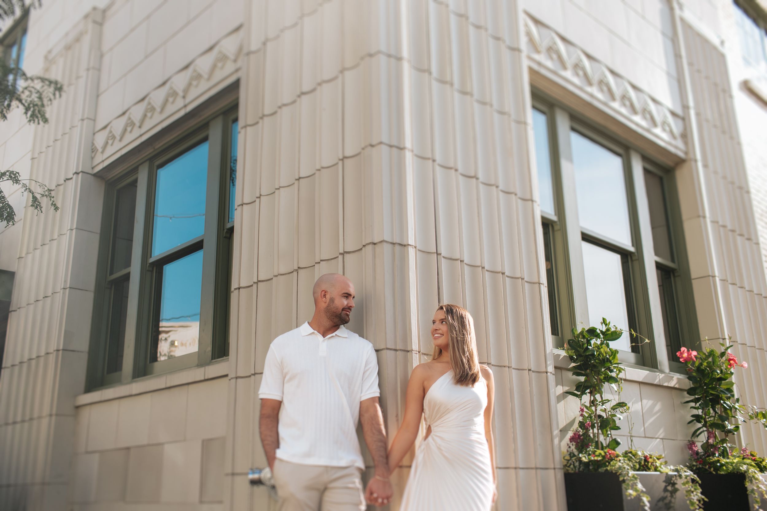 A couple shares a romantic moment in front of a grand building with white stone columns.