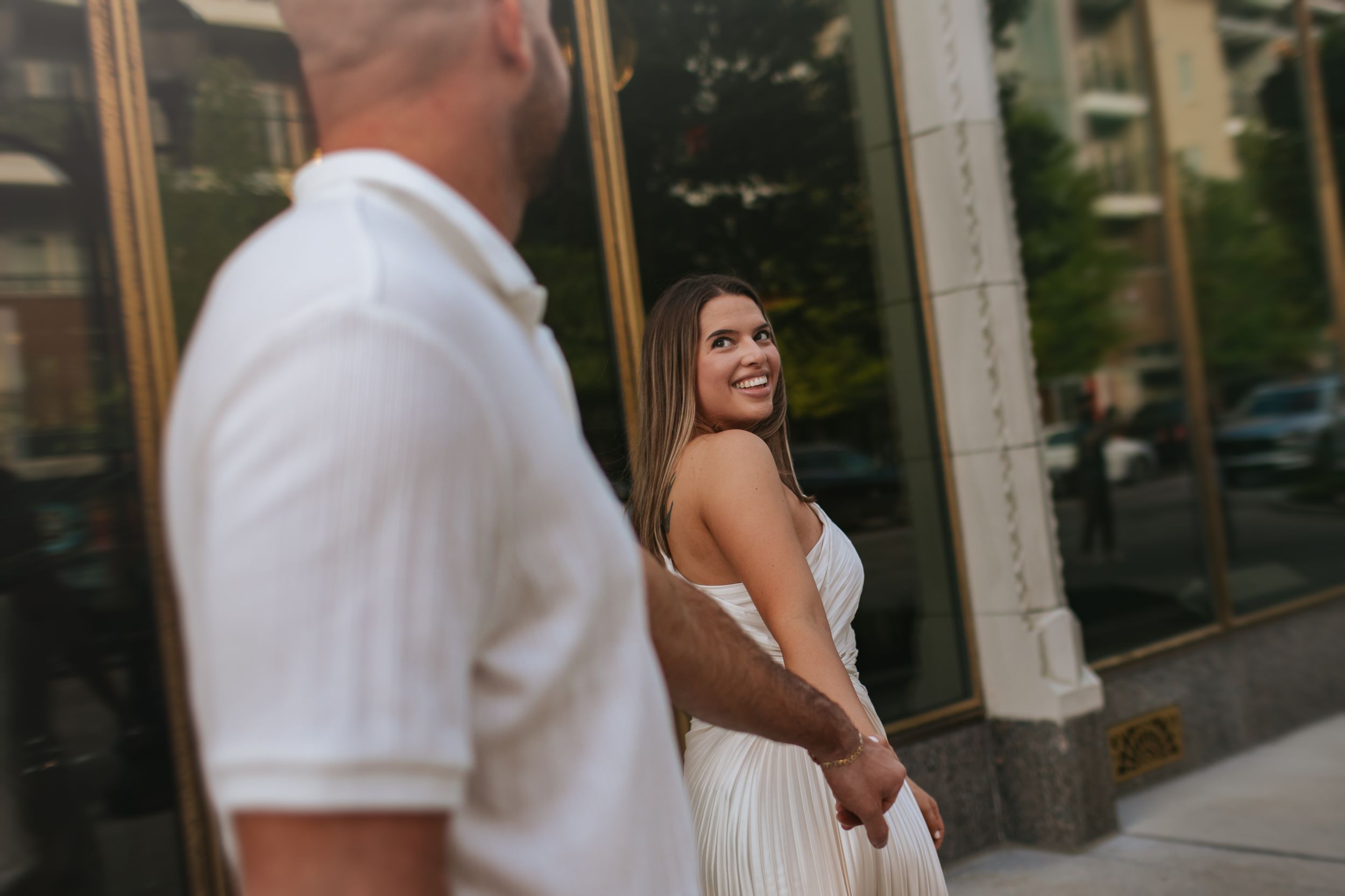 A couple in white outfits share a romantic moment while standing outside.