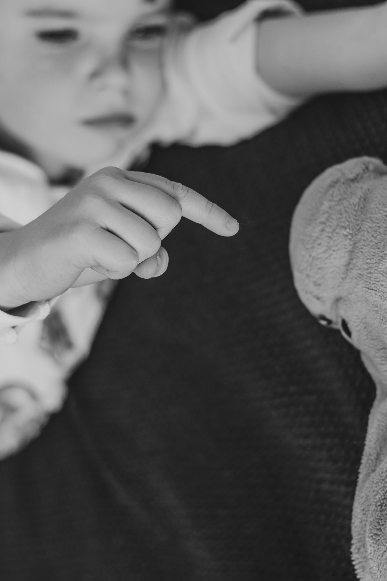 Black and white photo of a child pointing their finger at a stuffed animal toy | Annual Birthday Photos for Kids