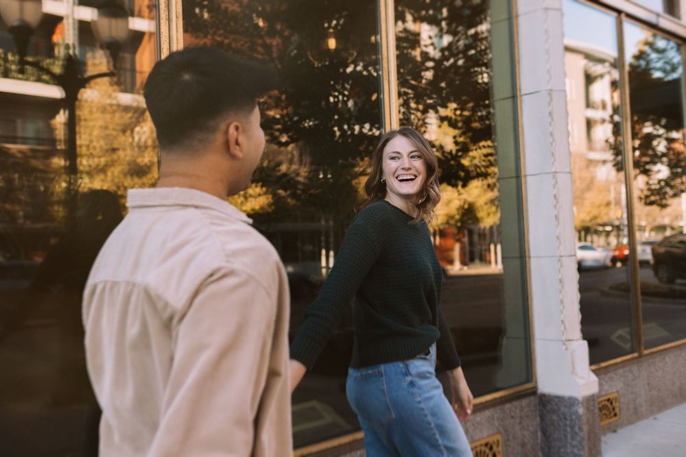 People walking and chatting outside a storefront at dusk with warm lighting in the background.