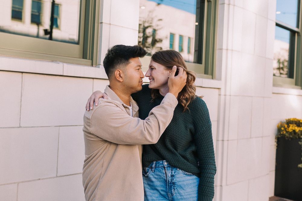 Romantic couple embracing against white building exterior wall.