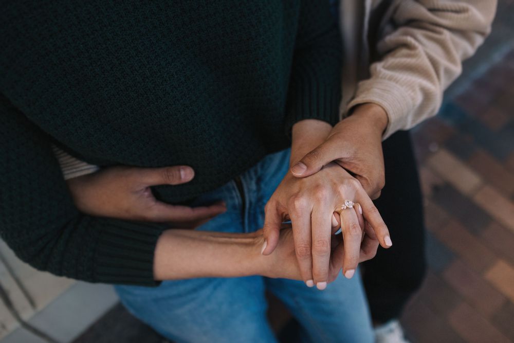 Close-up shot of hands with an engagement ring resting on blue jeans.