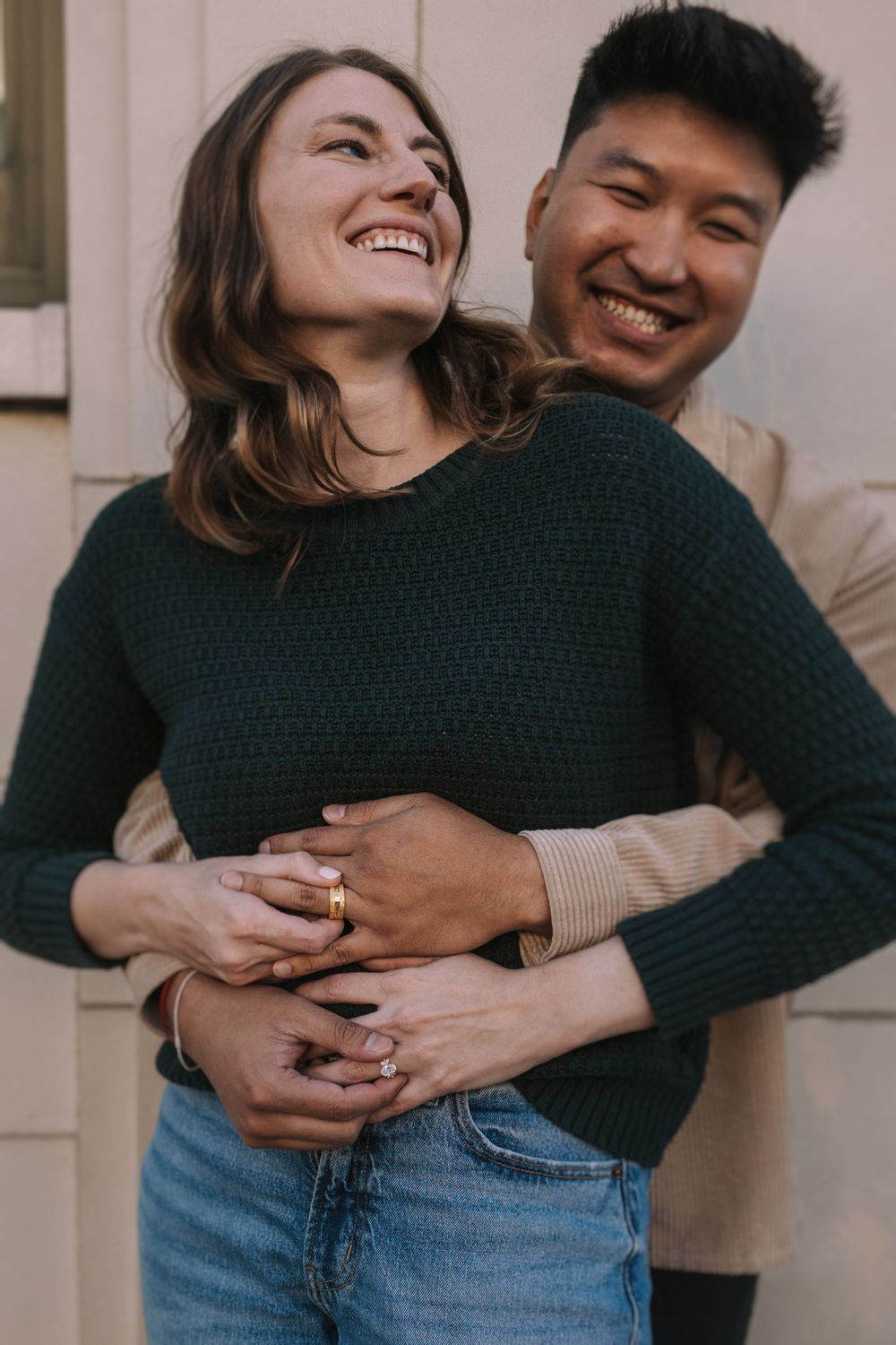 A couple shares a joyful embrace while wearing casual outfits of jeans and sweaters in a candid photo series.