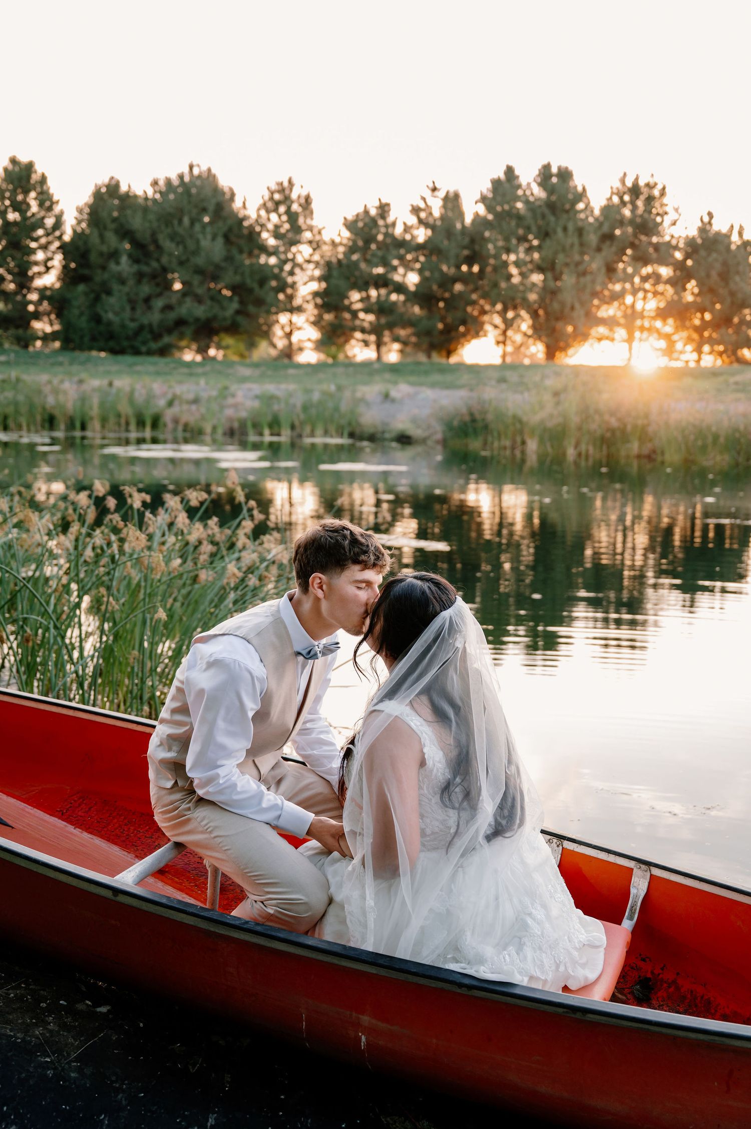 Sunset bride and groom portraits in a canoe on a pond