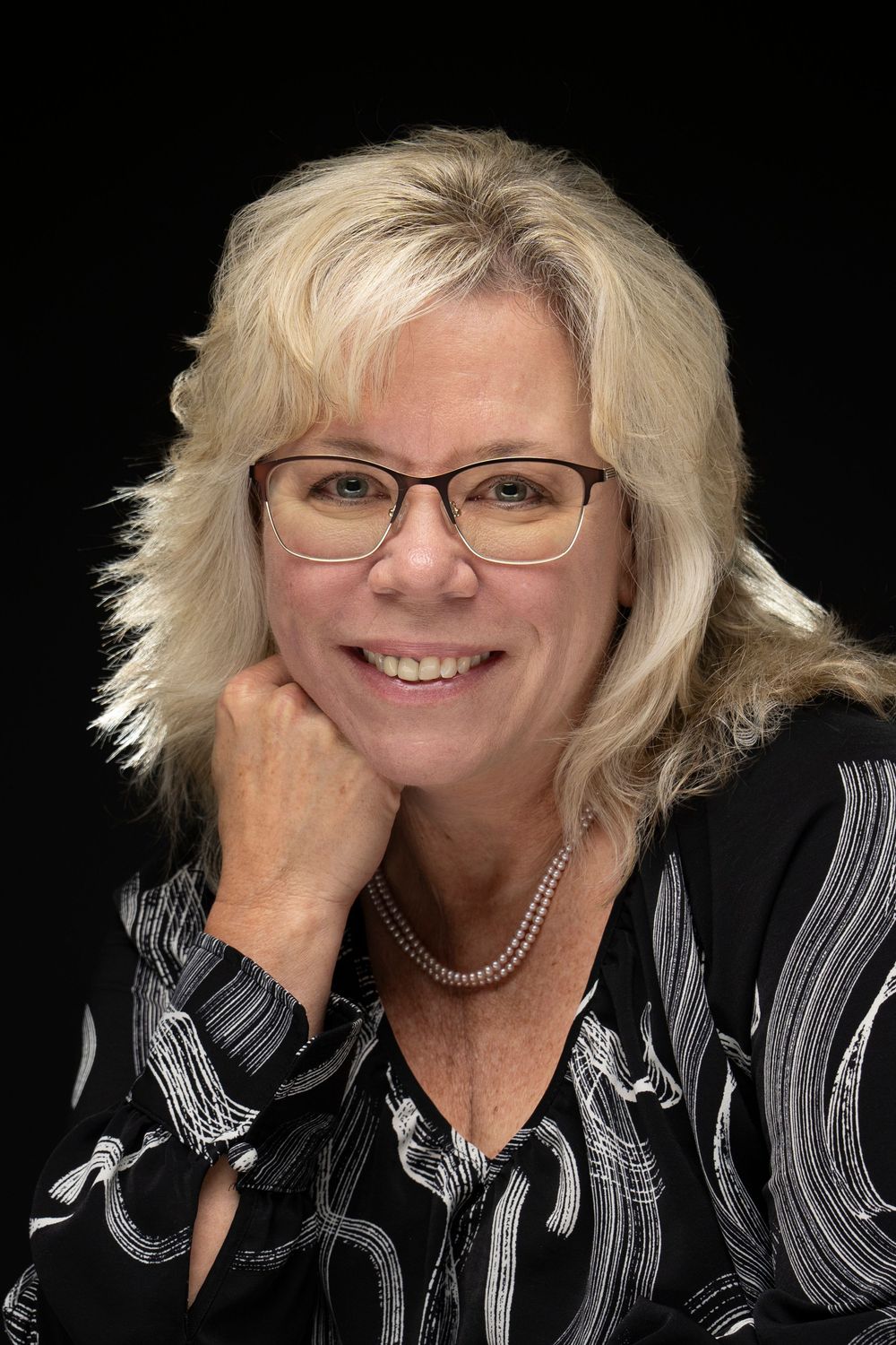 A series of headshots showing a person with blonde hair and glasses smiling in different poses against a dark background. In Orlando Fl
