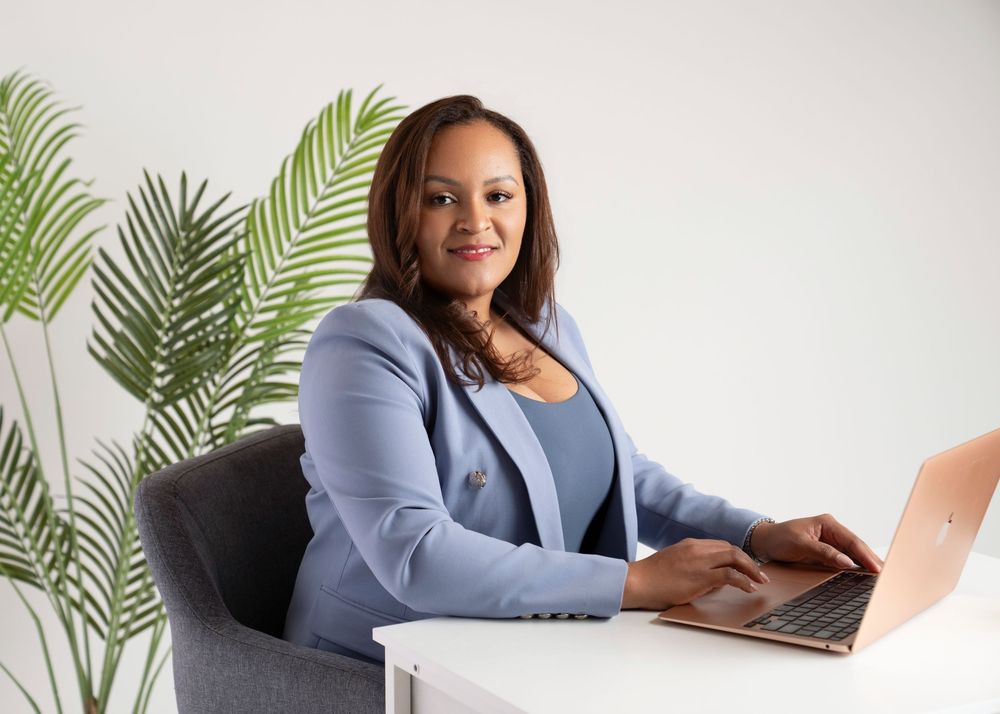 Professional in a light blue blazer works at a desk with tropical plants in the background. In studio in Orlando, Florida